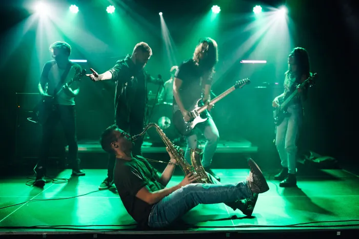Band performing live on stage with energetic musicians and vibrant green lighting during a boomer opinions event.