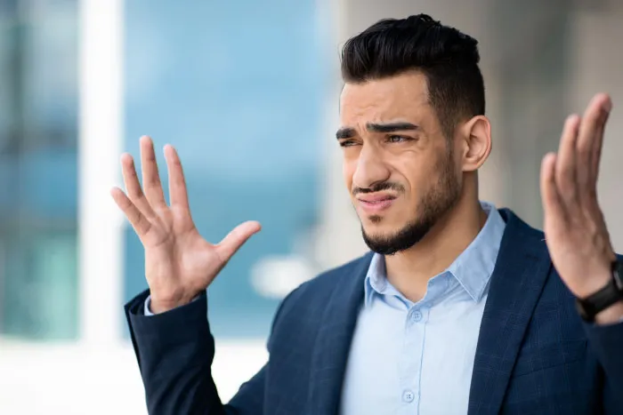 Young man in a suit making a confused gesture, illustrating common boomer opinions and generational reactions.