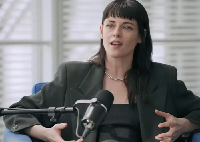 Woman with dark hair speaking in a podcast setup, discussing some of the worst celebrity infidelity scandals.
