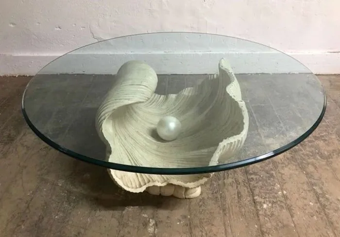 Glass coffee table with shell-shaped base and decorative pearl accent, showcasing cool interior design ideas.