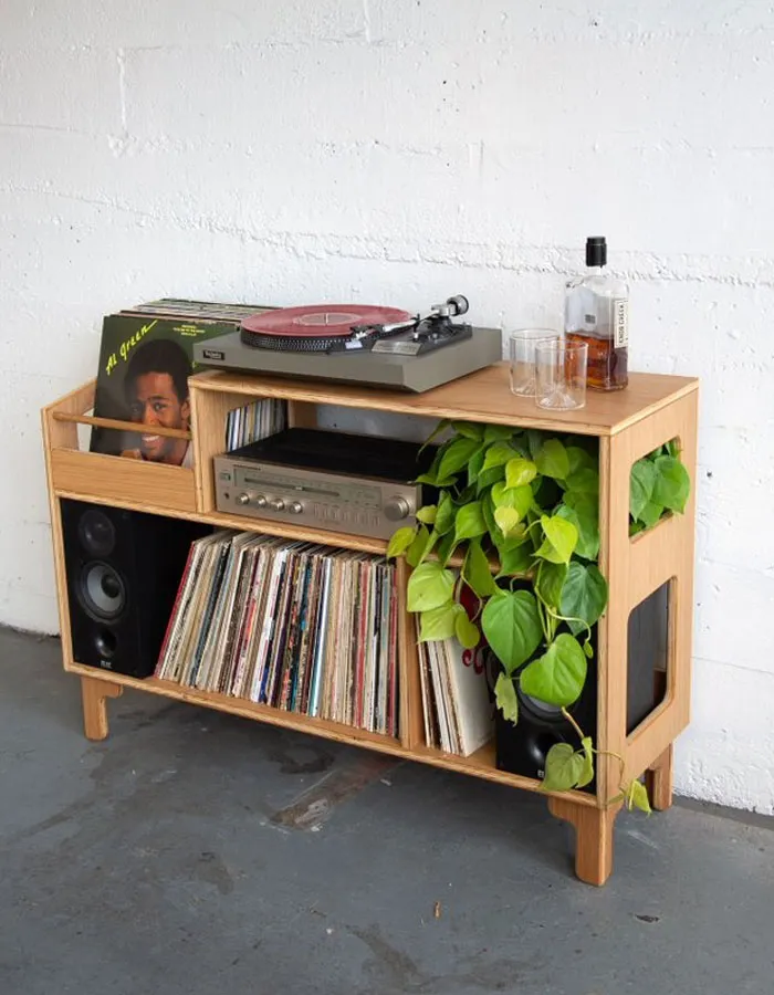 Modern wooden record player stand with speakers, vinyl collection, and greenery, showcasing cool interior design ideas.