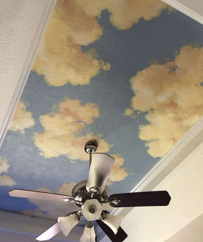Ceiling with cloud mural and ceiling fan showcasing cool interior design ideas for transforming home spaces.