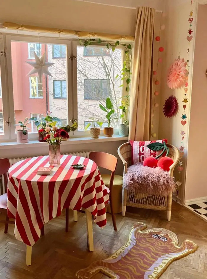 Cozy interior design ideas featuring a striped tablecloth, plants, colorful cushions, and decorative wall hangings in a bright room.