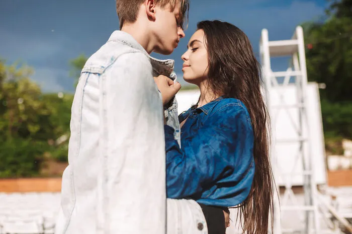 Teen couple nearly kissing outdoors, illustrating high school secrets discovered after graduation