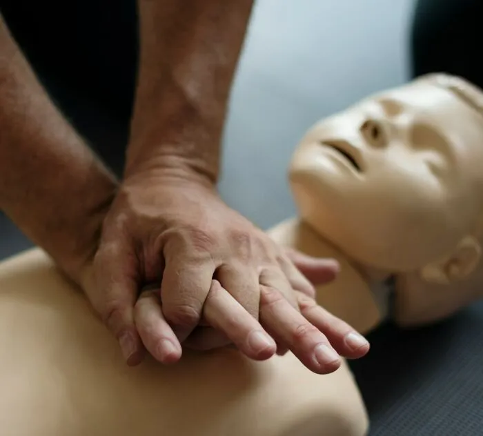 Hands performing CPR on a medical training mannequin demonstrating life-saving medical facts and techniques.