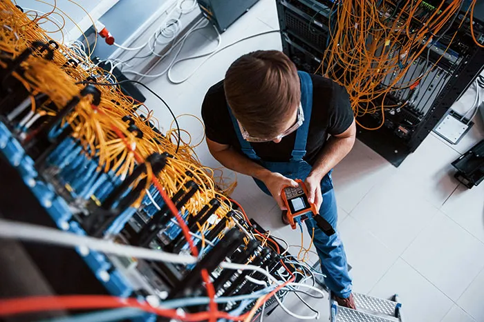 Technician working with tangled network cables and devices, illustrating dangerous things people willingly or unwillingly did.