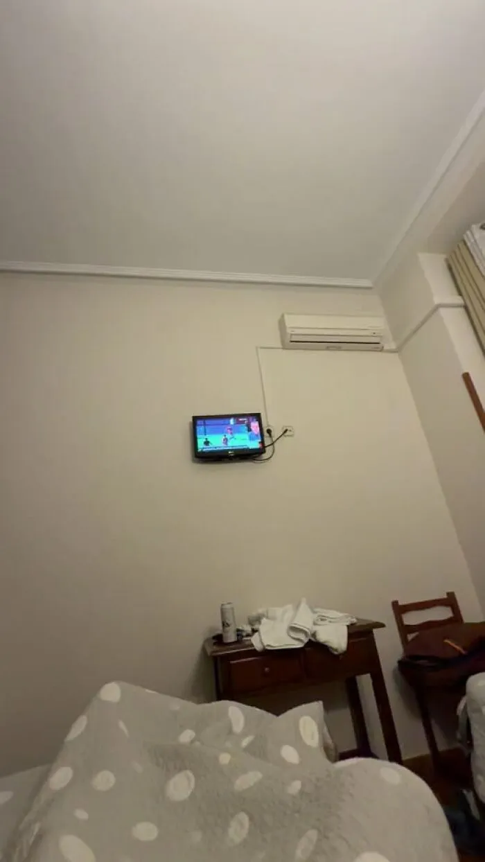 Habitación con televisor pequeño y aire acondicionado, mostrando escena que refleja un día en que todo salió mal.