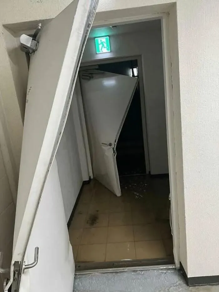 Puerta de emergencia rota y dañada en pasillo, ejemplo claro de algo que salió mal en un día desafortunado.