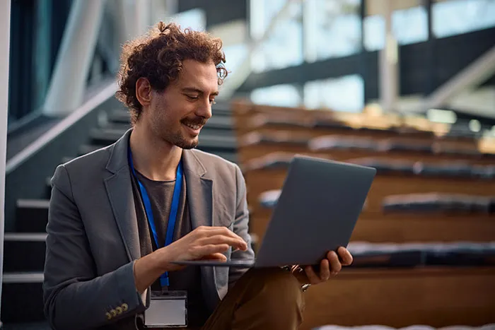 Young gifted man working on a laptop in an auditorium, reflecting potential for great achievements in his career.