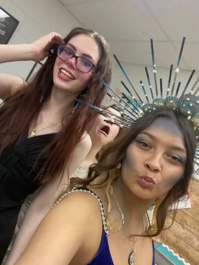 Two young women with stage makeup and a crown pose for a playful selfie showcasing magical and mildly cursed makeup looks.
