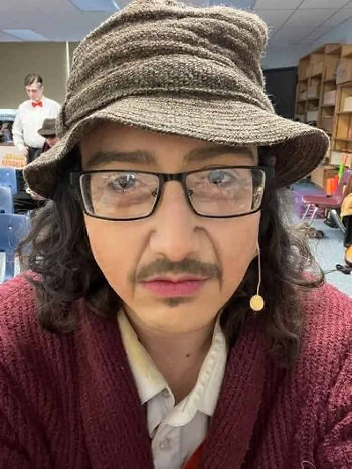 Person wearing glasses, hat, and stage makeup with a mustache, showcasing magical stage makeup looks in a theater setting.