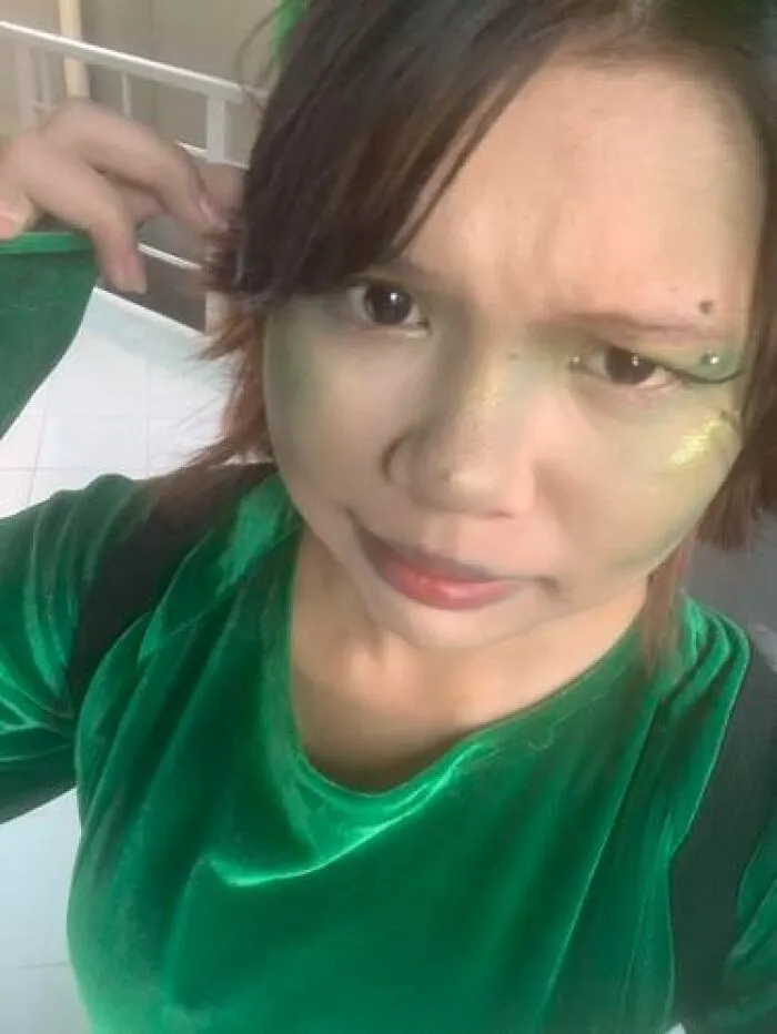 Person in green velvet top with subtle stage makeup including green highlights and face gems, showcasing stage makeup look.