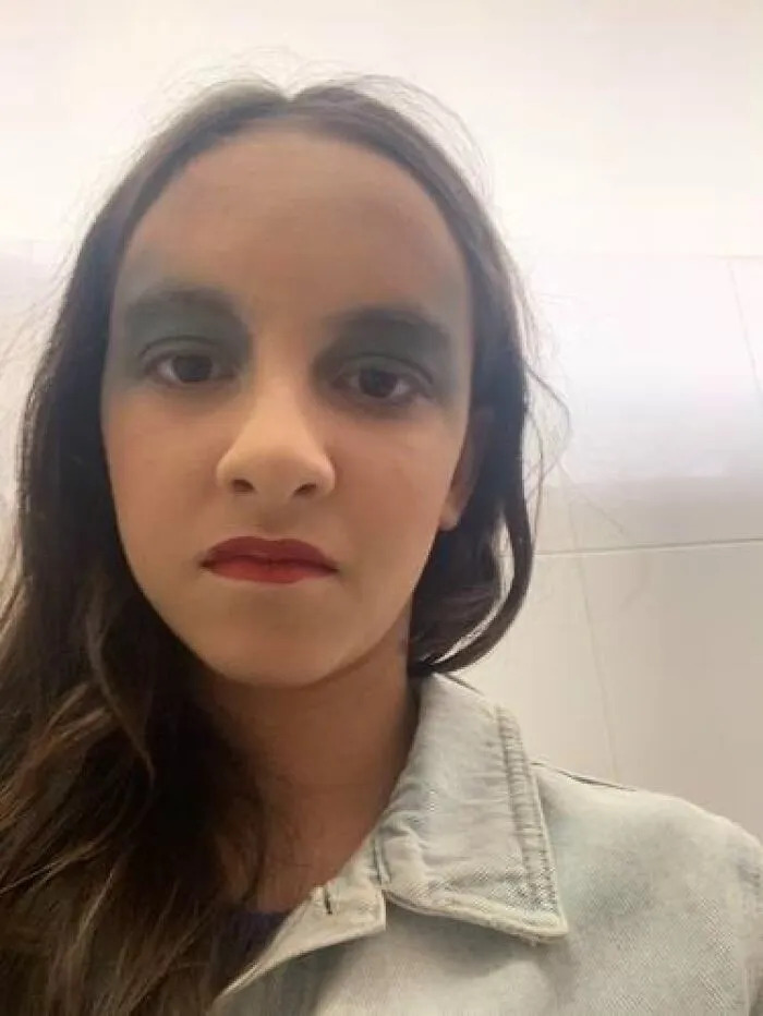 Young person with stage makeup featuring dark eyeshadow and bold lipstick, showing magical and mildly cursed looks.