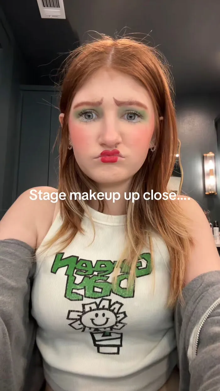 Young woman with exaggerated and quirky stage makeup close up, showcasing unique theatrical makeup style.
