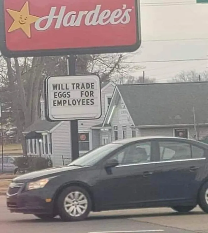 Hardee's sign outside with message offering eggs in exchange for employees, highlighting a dystopia job market reality.