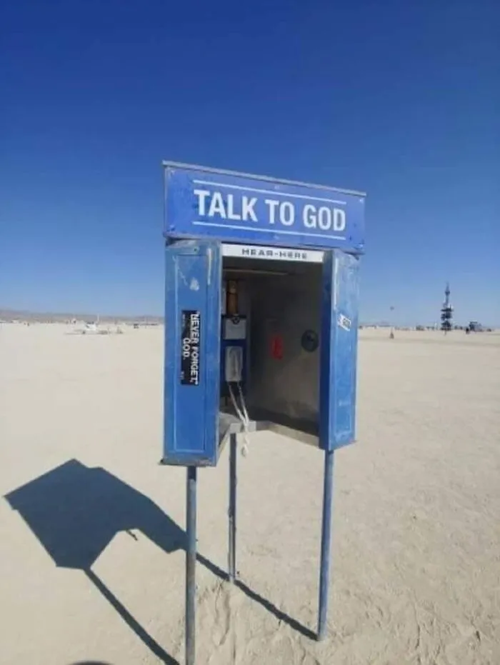 Blue phone booth labeled Talk to God standing alone on a desert plain symbolizing dystopia and surreal normality.