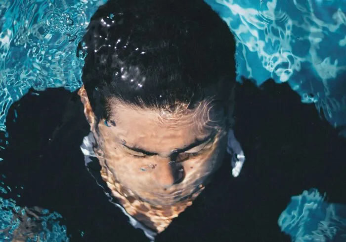 Man submerged in water, eyes closed, illustrating unusual medical facts that sound made up but are true.