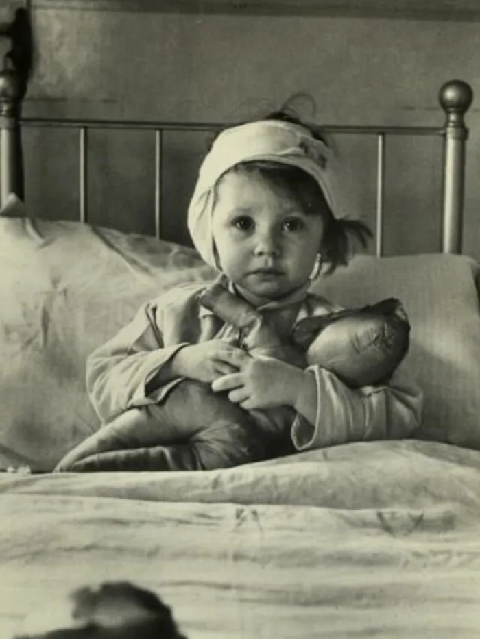 A Brave Little 3-Year-Old, Eileen Dunne, Sits In Bed With Her Doll At Great Ormond Street Hospital, After Being Injured During An Air Raid On London, During The Blitz Of London By The Luftwaffe, In September, 1940