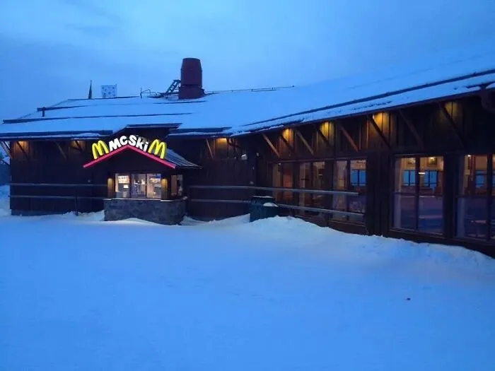 Wooden building in snow at dusk with glowing McSkiM sign, showcasing impressive things countries implemented in cold regions.