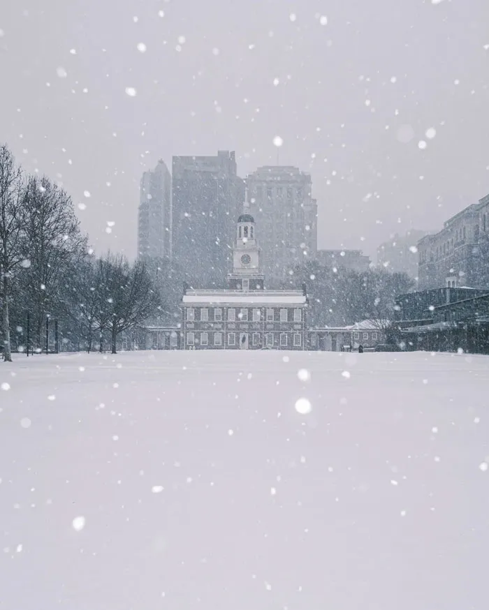 Heavy snowstorm hitting the U.S. city with historic building and downtown skyscrapers covered in thick snow.