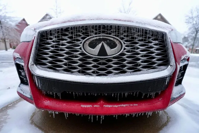 Front grille of a red car covered in ice and snow during a heavy snowstorm in the U.S.