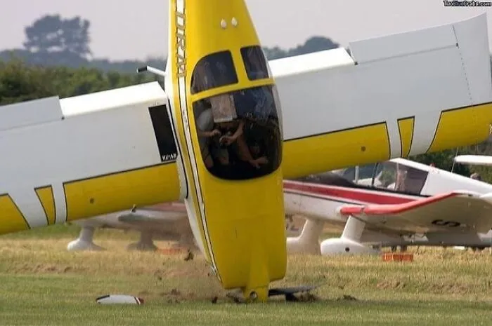 Small yellow plane nose-diving into grass during landing attempt, an internet photo that was not what it seemed.