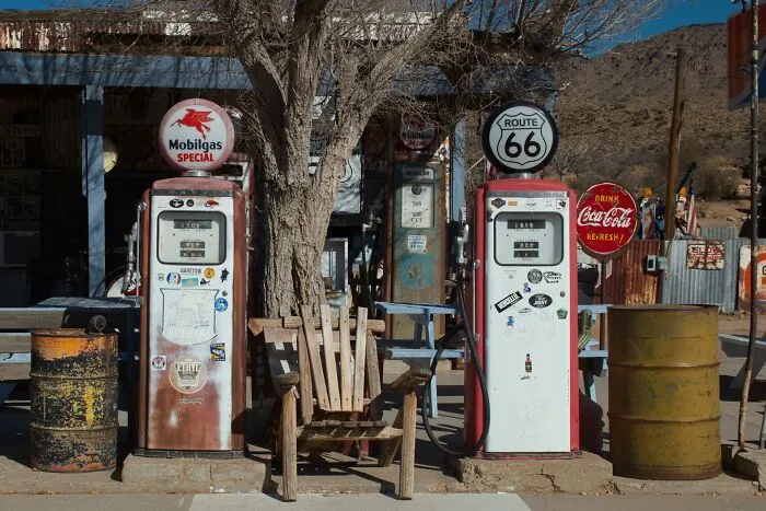 Vintage gas pumps and wooden chairs along Route 66 symbolizing progress and hope in America beyond negative headlines.