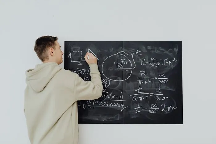 Young man writes complex equations on blackboard, illustrating creepiest displays of intelligence