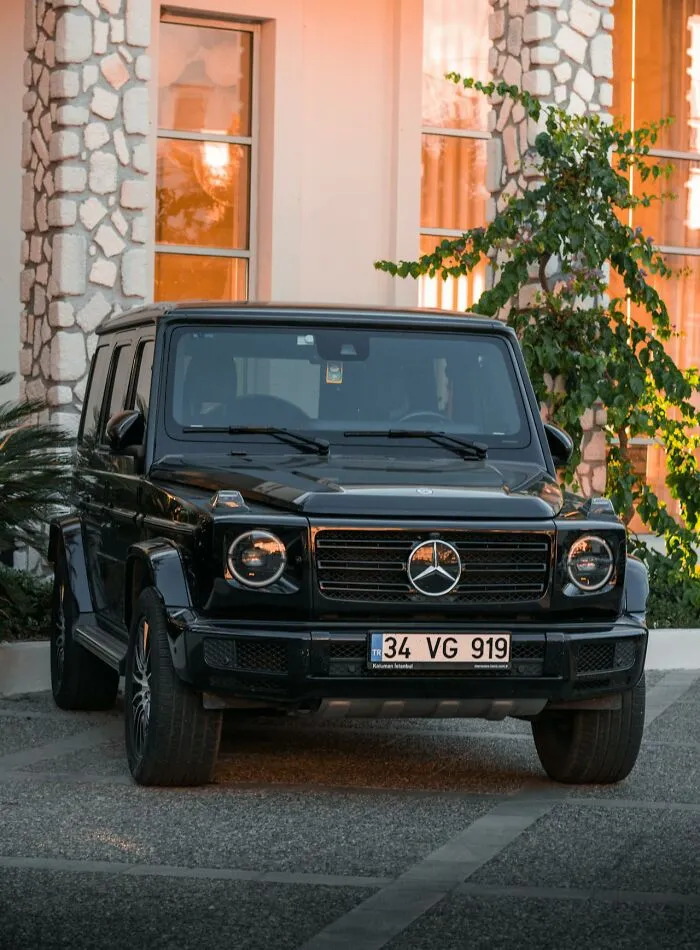 Black luxury SUV parked by a mansion entrance, illustrating rich people showing how far from reality they are.