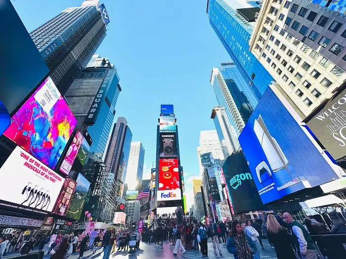 Times Square bustling with crowds and bright digital billboards showcasing brands in a popular tourist attraction.