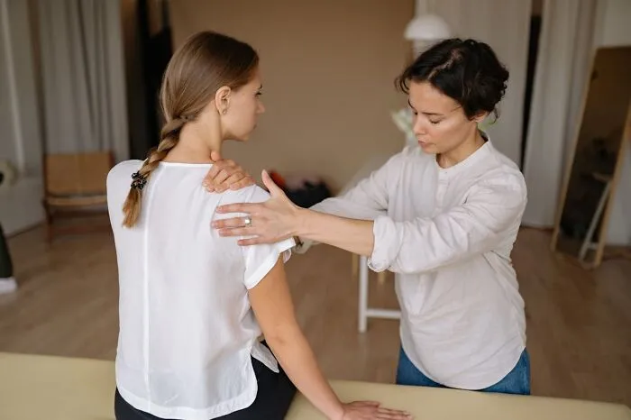 Physical therapist examining woman's shoulder in clinic, stock photo illustrating rained frogs bizarre true story