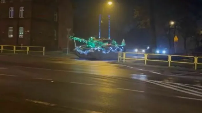 Tank decorated with Christmas lights parked on a street at night, capturing Eastern European experience humor.