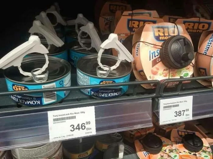Canned fish products with plastic security seals on supermarket shelves, illustrating Eastern European shopping scene.