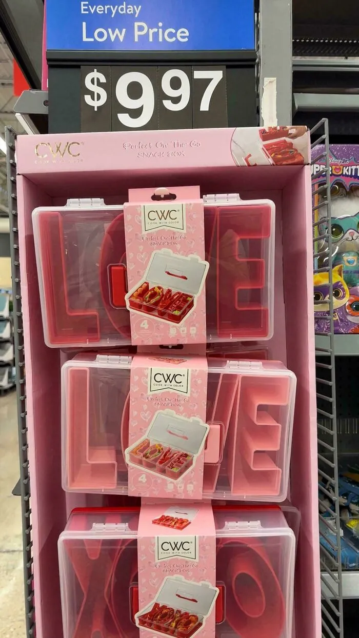 Plastic snack boxes spelling love stacked under a low price sign highlighting the impact of consumerism products.