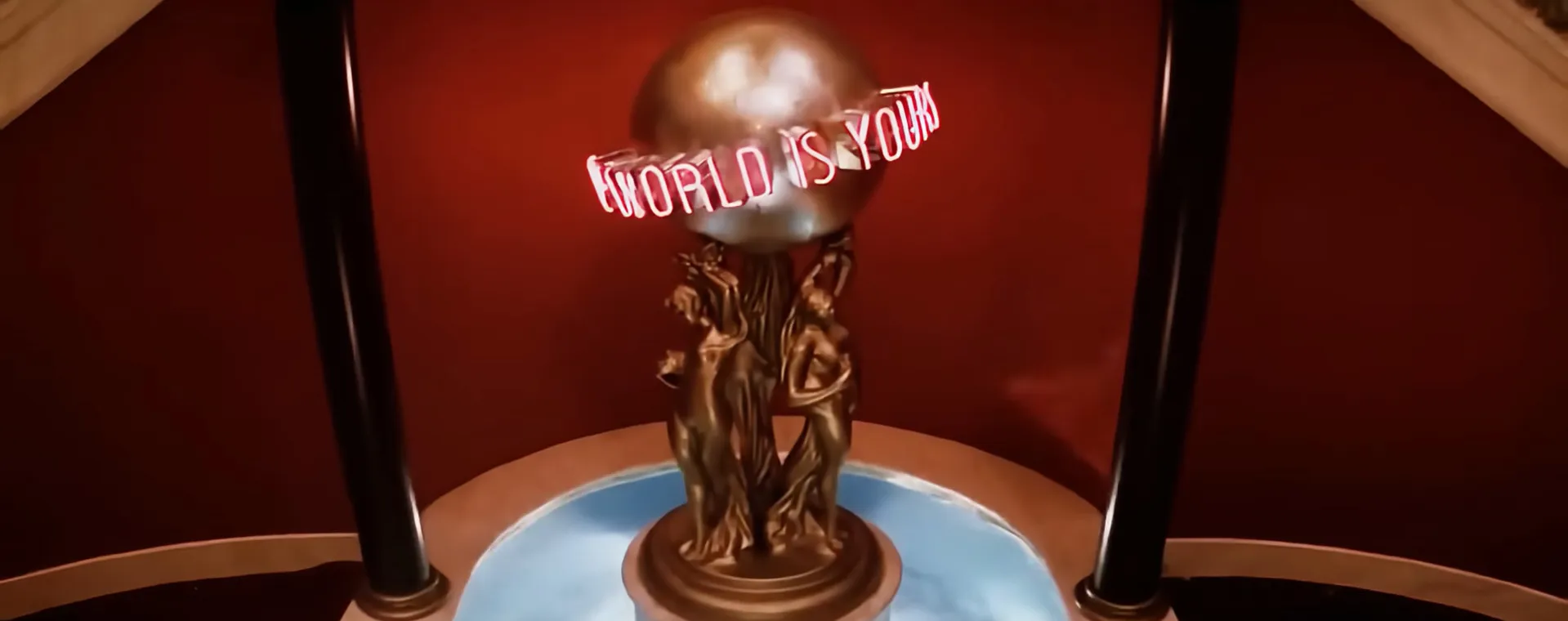 Bronze statue with a glowing neon sign saying World is Yours in a film final scene setting.