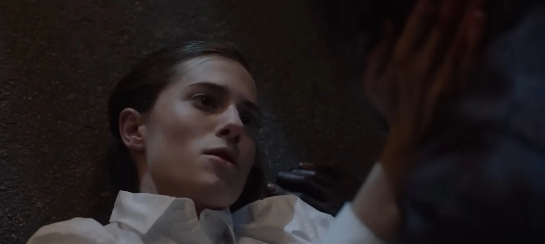 Close-up of a woman lying down with a distressed expression in a dramatic movie final scene.