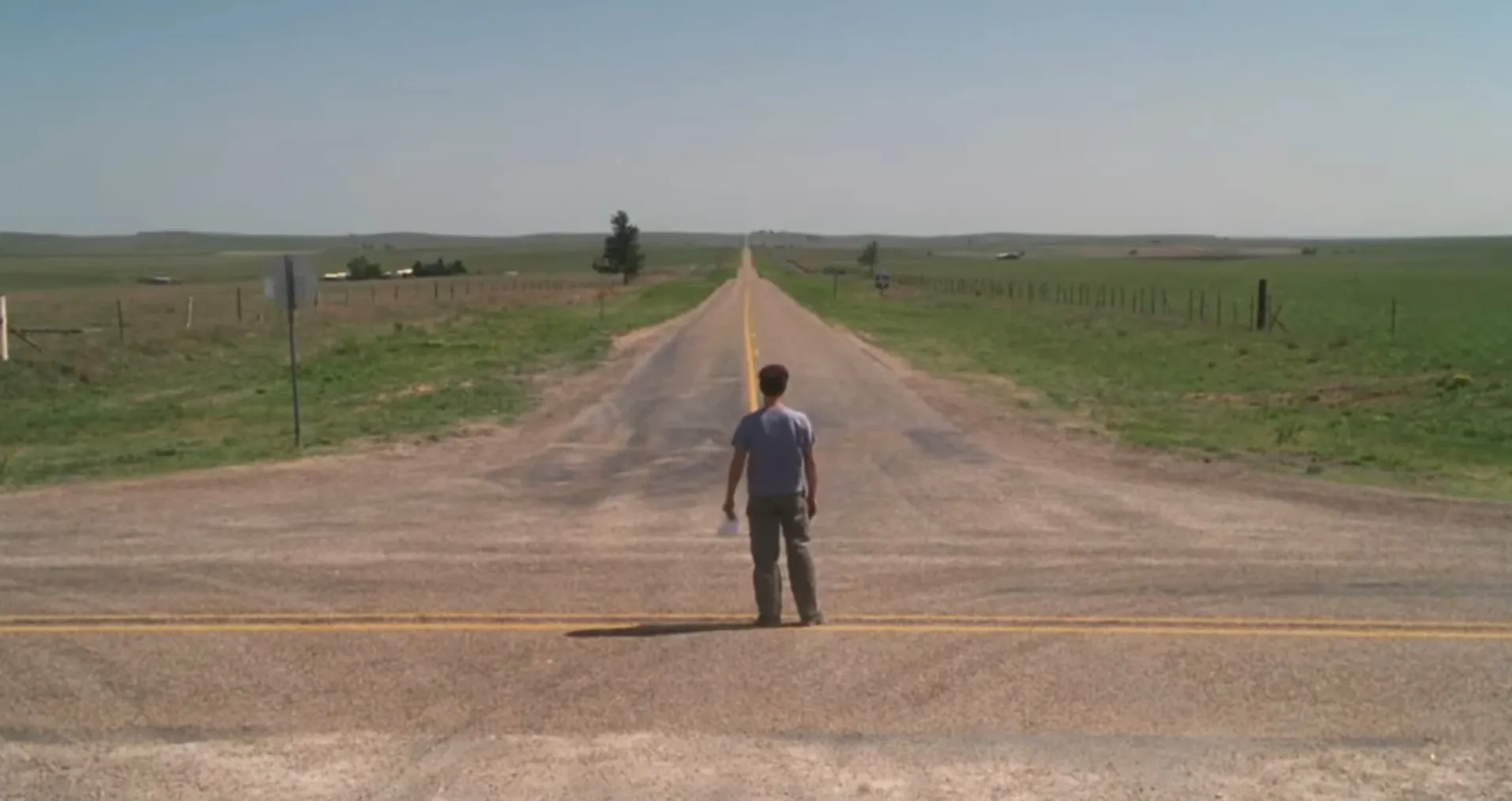 Man standing alone on an empty rural road in a film final scene, evoking questions about what movie has this ending scene