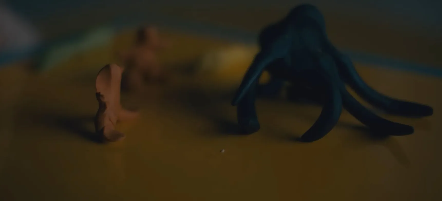 Clay figures of two small characters facing a larger black octopus-shaped figure in a dimly lit setting, movie final scenes.