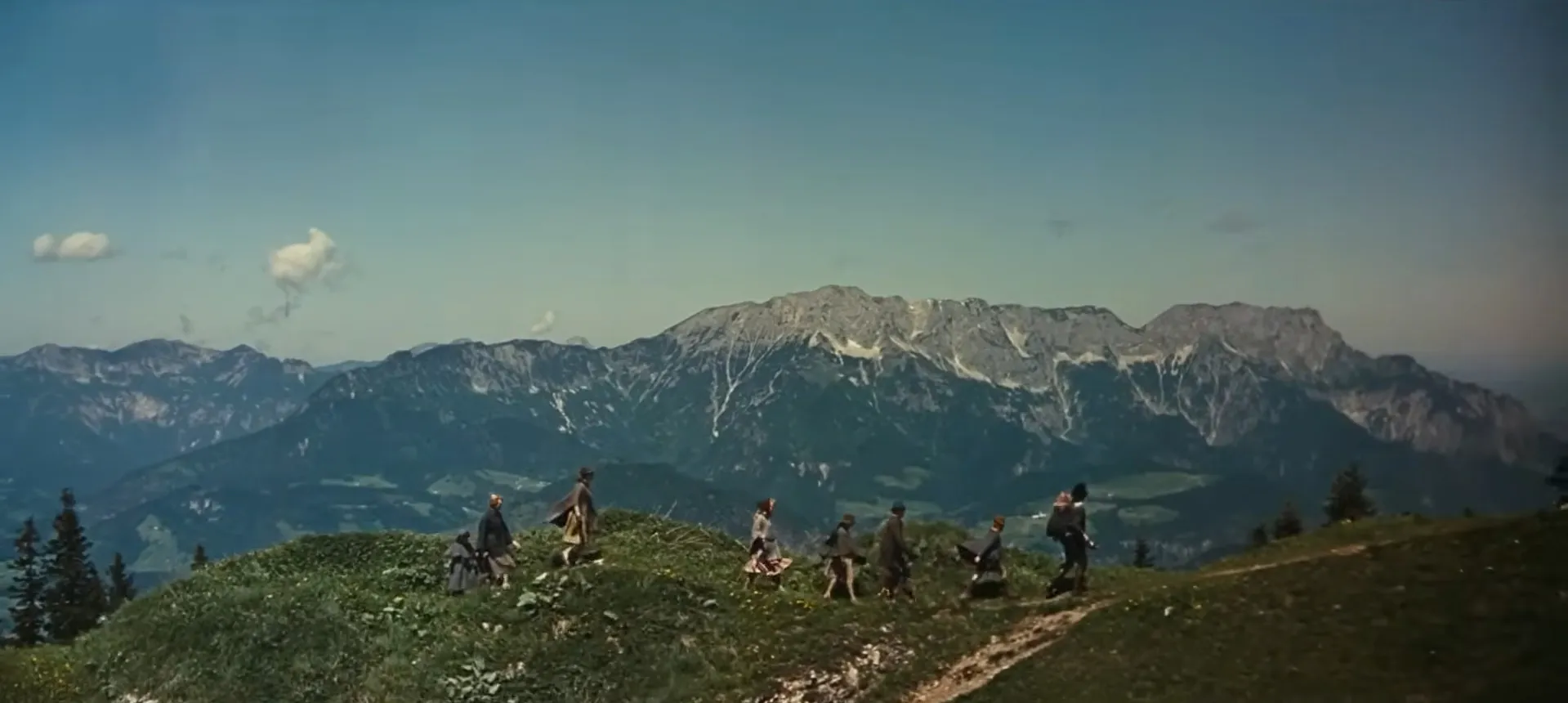 A group of people hiking on a mountain trail with scenic views in a movie final scenes setting.