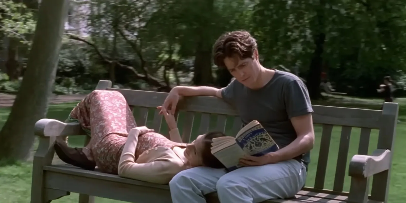 Young couple on a park bench in the movie final scenes, with the woman lying down and the man reading a book.