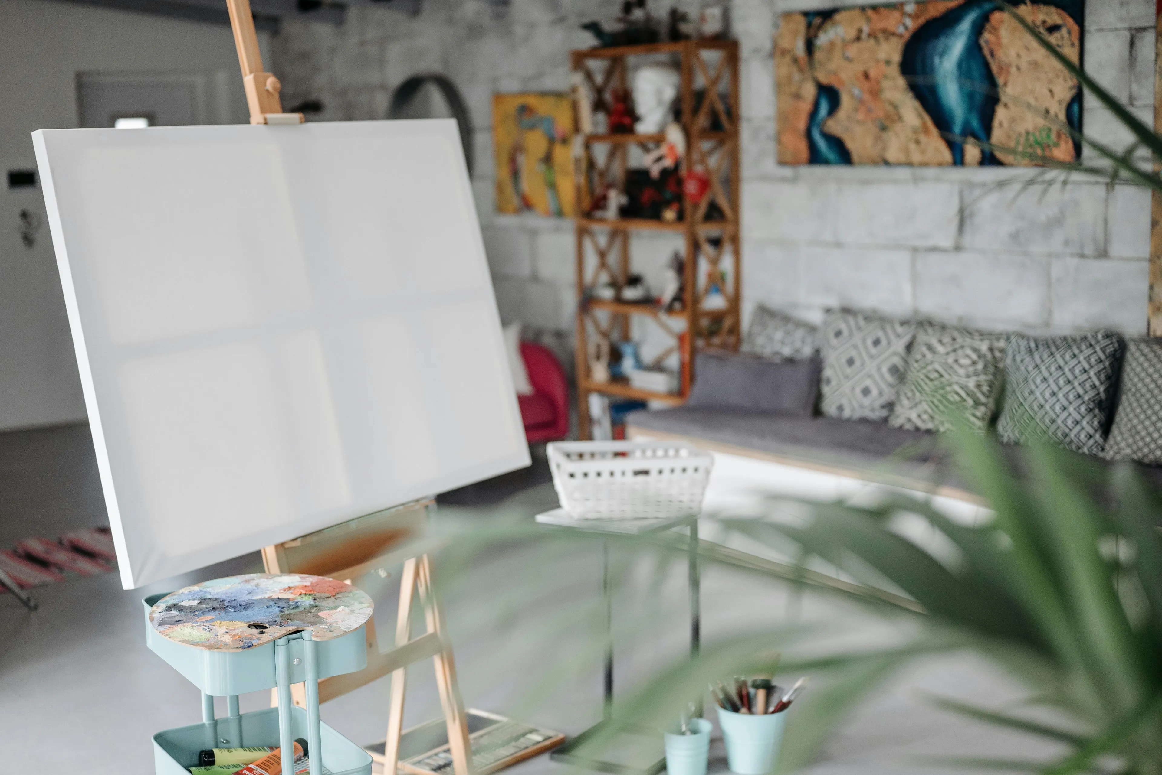 Empty canvas on easel in art studio with painting supplies, illustrating art general knowledge about triptych panels.