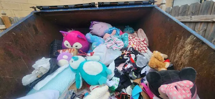 A dumpster filled with a bounty of plush toys and other items, a treasure trove for people dumpster diving.