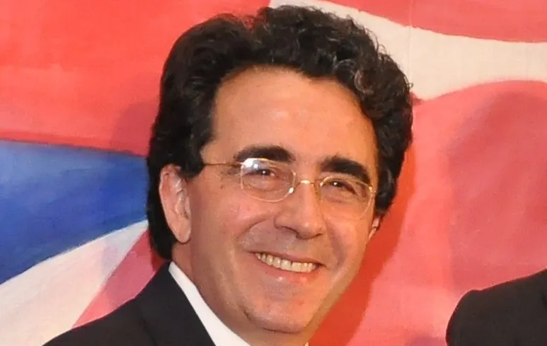 Santiago Calatrava smiling, wearing glasses and a dark suit, known as the architect-artist behind Sagrada Família in Barcelona.