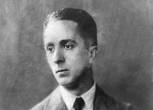 Black and white portrait of Norman Rockwell in a suit and tie, looking to the side with a neutral expression.