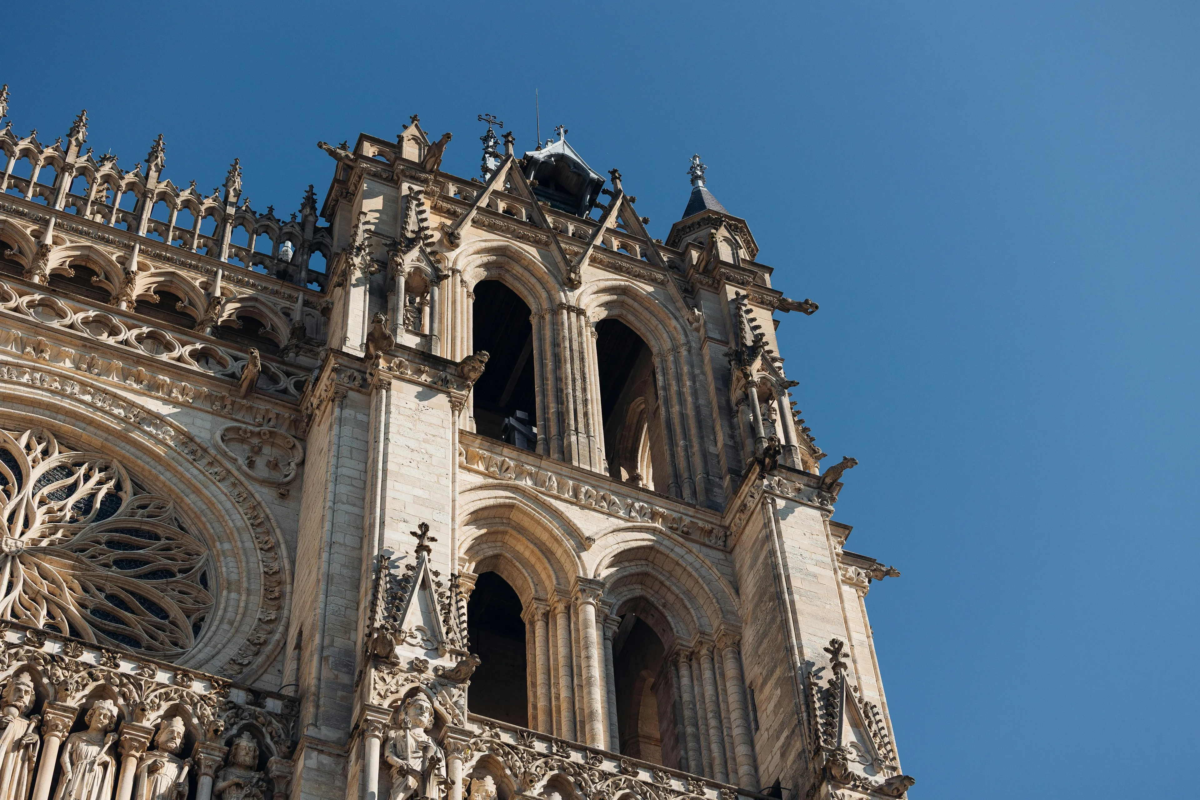 Gothic architectural style featuring pointed arches, ribbed vaults, and detailed stone carvings under a clear blue sky.