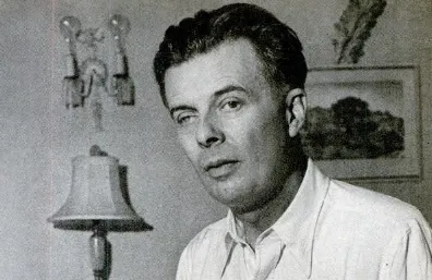 Black and white photo of Aldous Huxley in a room with a lamp and framed artwork in the background.