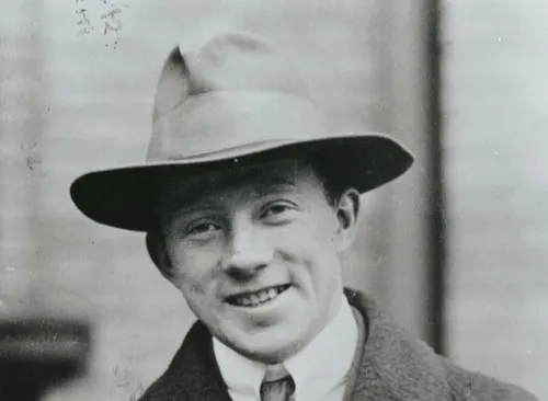 Young Werner Heisenberg wearing a fedora and coat, smiling in a black and white vintage photograph.