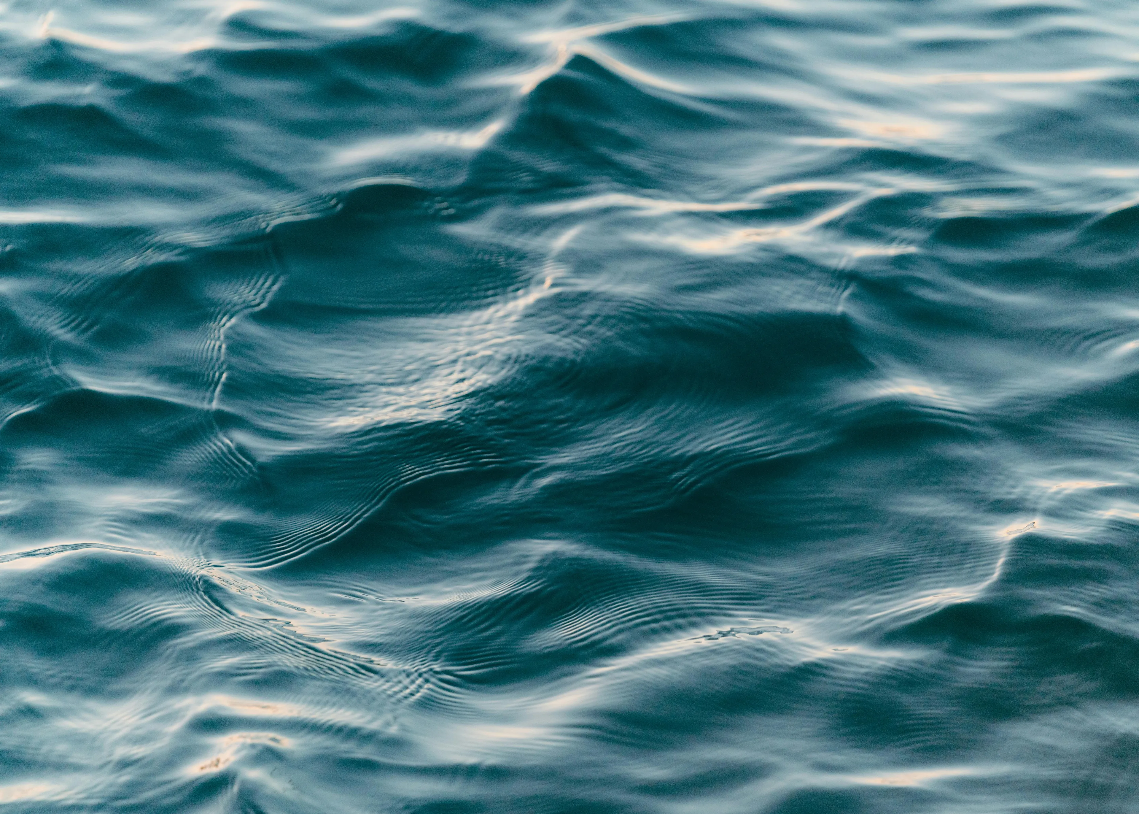 Rippling water surface reflecting light, related to structures designed to hold back water and generate electricity.