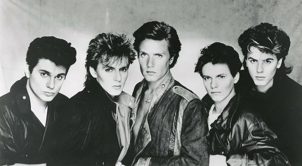 1980s band known for hits including Hungry Like the Wolf, posing together in leather jackets with 80s hairstyles.
