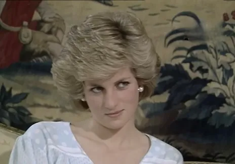 Princess Diana in the 1980s, wearing a white polka dot blouse with short styled hair and pearl earrings.